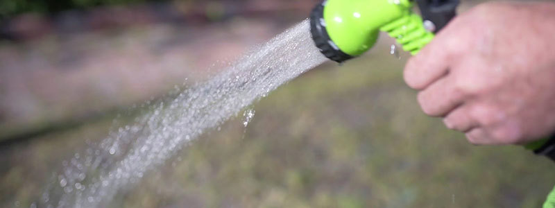 En sprøjtepistol spreder vand over en græsplæne