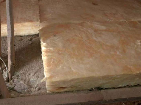 Ny glasuld ligger ovenpå et allerede eksisterende lag af isolering på et loft