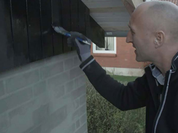 Træværket på gavlen af huset males med træbeskyttelse
