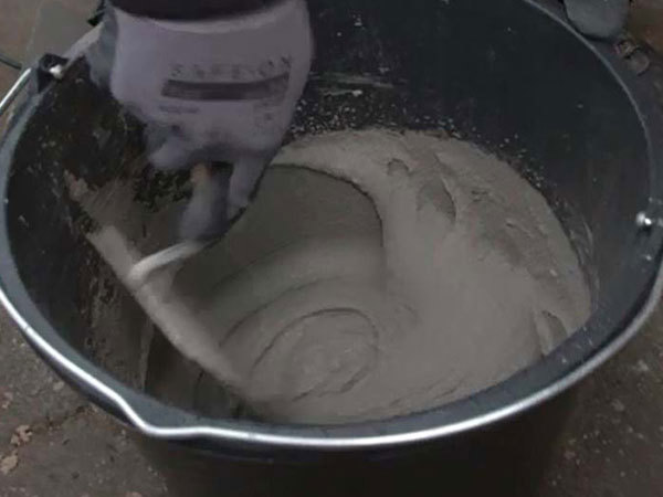 Mørtel blandes med en murerske i en spand