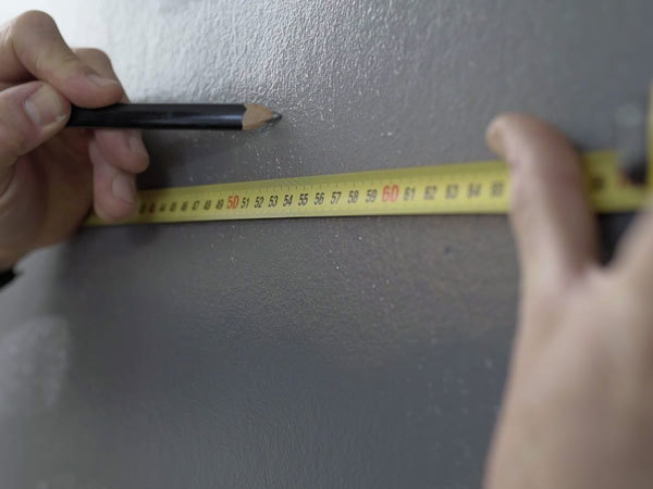 Væggens bredde måles og der afsættes markeringer for hver bane tapet