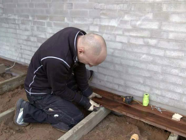 Terrassebrædder monteres på fundamentet ved husmuren