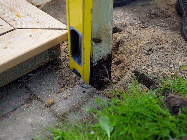 Stolpen stampes fast i støbesand med et vaterpas