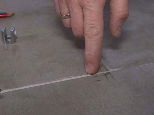 Finger peger på markering på flisegulv