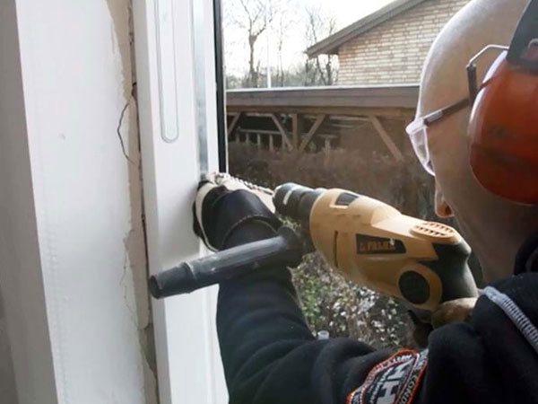 Boremaskine borer igennem vinduesrammen og ind i muren